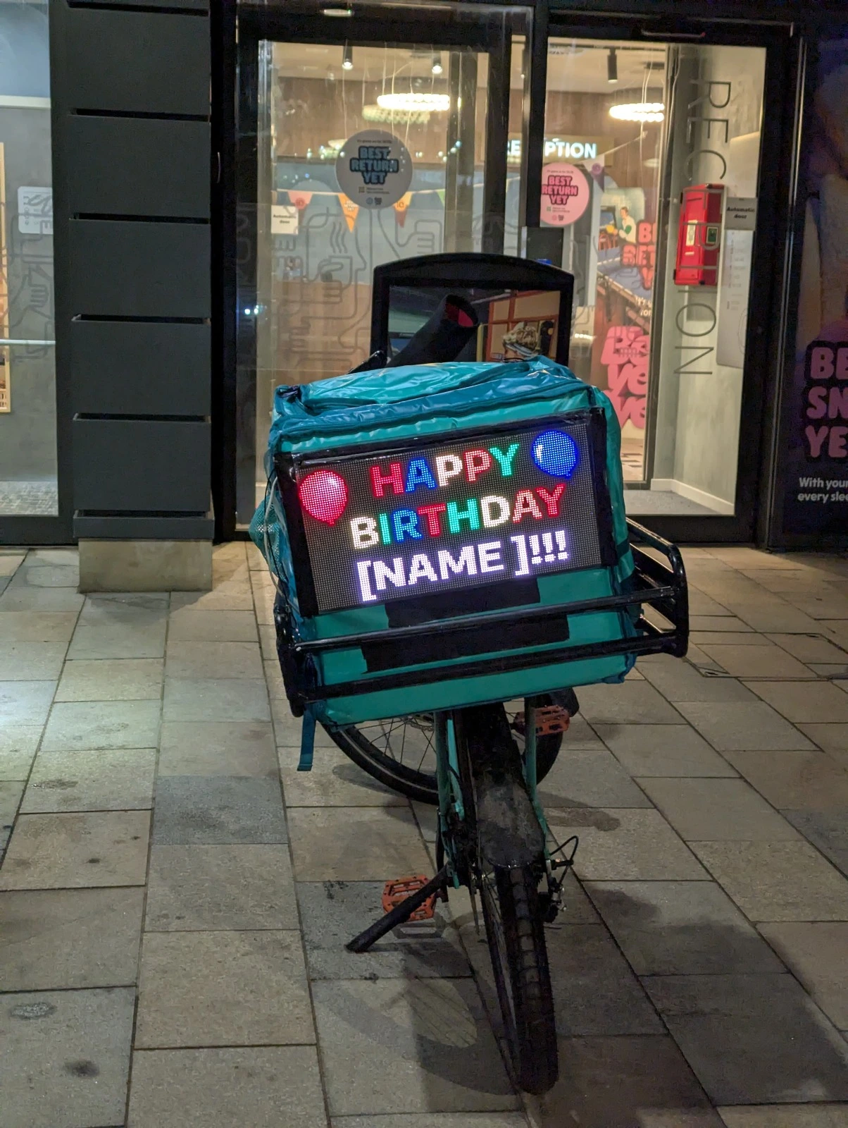 Dynamic display screen showing rotating advertisements on delivery bike in Edinburgh city center